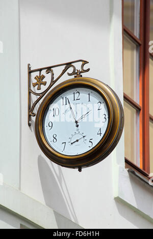 old round street watch hanging on a white wall Stock Photo