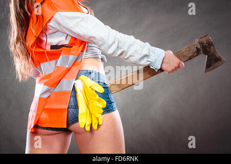 Closeup of woman wearing safety workwear holding axe chopper. Strong girl feminist working in man profession. Independent female Stock Photo
