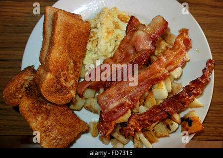 a plate of breakfast food including bacon, eggs, toast and homefries Stock Photo