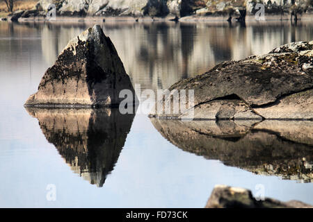 Rock reflection in lake Llynnau Mymbyr in Dyffryn Mymbyr, a valley running from the village of Capel Curig Snowdonia Wales Stock Photo