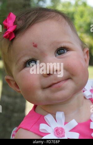Beautiful little baby girl all dressed up for Easter Sunday. She has a beautiful heart shaped birthmark on her forehead. Stock Photo