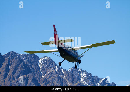 Milford Sound Flights Gippsland GA8 plane landing at Queenstown Airport, and The Remarkables mountains, Otago, South Island, NZ Stock Photo