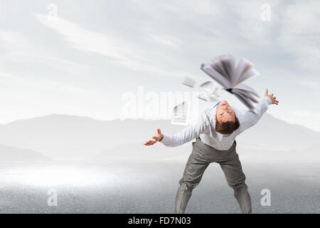 Young businessman trying to evade from thrown book Stock Photo