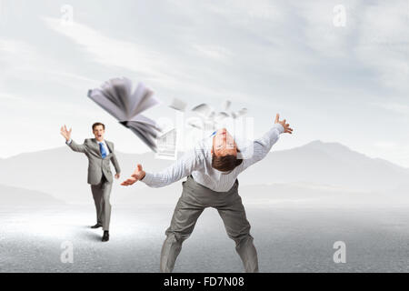 Young businessman trying to evade from thrown book Stock Photo