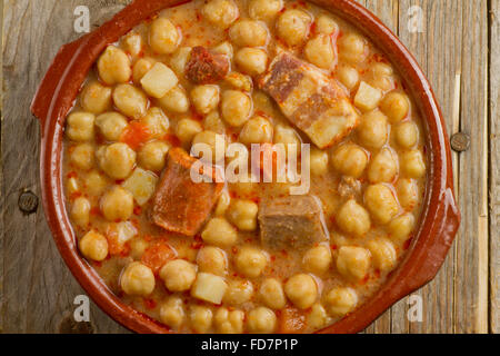 Spanish Cocido in an earthenware pot on wooden background Stock Photo