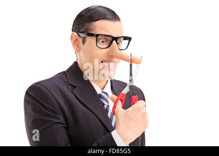 Worried businessman with long nose cutting the tip of his nose with scissors isolated on white background Stock Photo