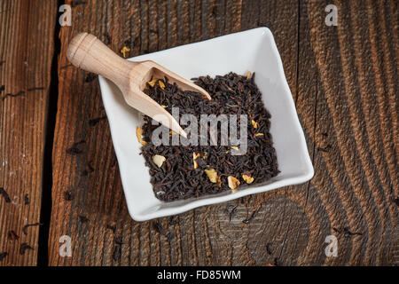 Black tea leaves in a white bowl on a brown wooden table Stock Photo