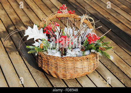 Composition of fir branches, rowan and apples in wicker basket on wooden background. Stock Photo
