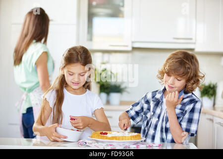 Boy and girl baking a fruit cake together in the kitchen Stock Photo