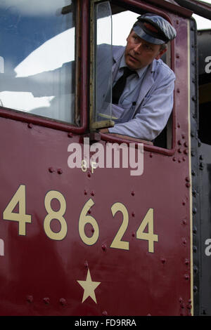 Train driver on 8F 48624 starts his train away from the station with a facial expression showing concentration, Great Central Railway, Loughborough. Stock Photo