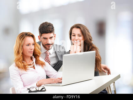 Happy business team analyzing financial data on laptop while sitting at office. Stock Photo