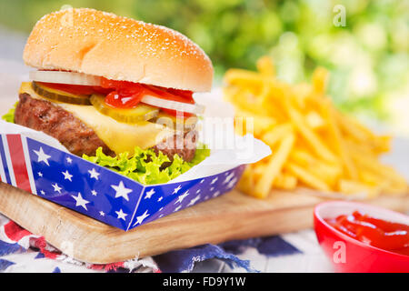 A tasty burger with fries on an outdoor table. Stock Photo