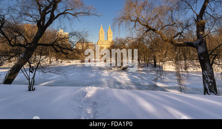 Winter sunrise on The Lake, frozen and covered in snow, in Central Park, with view on Upper West Side buildings. New York City Stock Photo