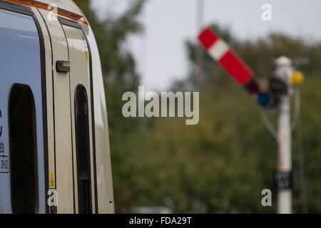 Arriva Trains Wales ATW Alstom Class 175 has the clear green signal from Helsby HSB station with a traditional semaphore signal shown in soft focus. Stock Photo