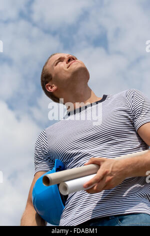 Young male architect holding plans and smiling. Stock Photo