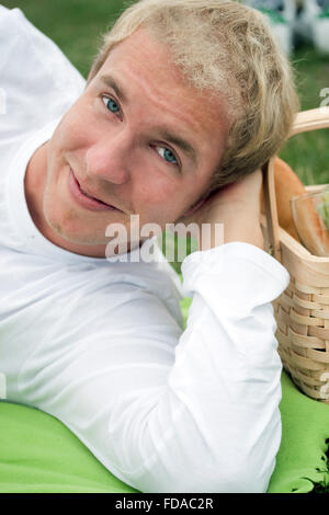 Young smiling man lying down in a picnic setting. Stock Photo