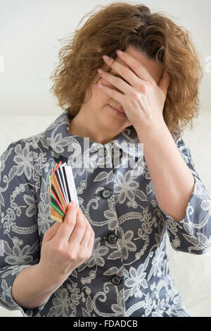 Upset woman with credit cards covered  face his hand Stock Photo