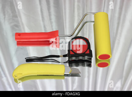 The roller for wallpaper, roulette and knife with reflection on a light background. Stock Photo