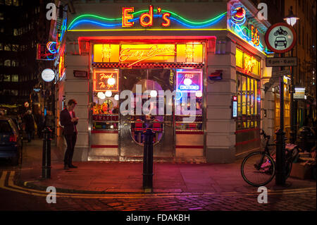 Man on mobile phone below neon lights of Ed's Diner, Soho, London Stock Photo