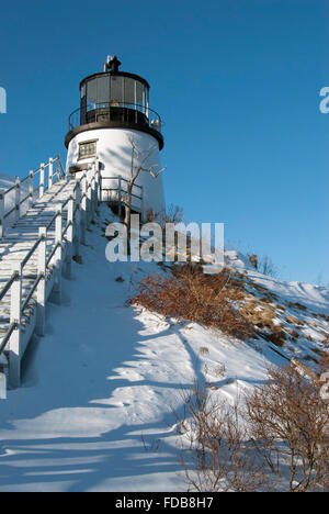 Historic Owls Head Lighthouse sits on a snow covered cliff in Maine. Stock Photo