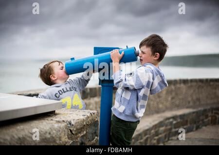 MODEL RELEASED. Two boys using coin operated telescopes at the seaside. Stock Photo
