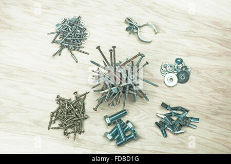 Piles of nails, screw, bolts, washers, a clamp, rivets, and misc. things found on a workbench shot flat lay from overhead on woo Stock Photo