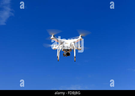 White remote controlled drone equipped with high resolution video camera hovering in mid air Stock Photo