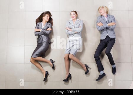 Young people in business suits lying on floor Stock Photo