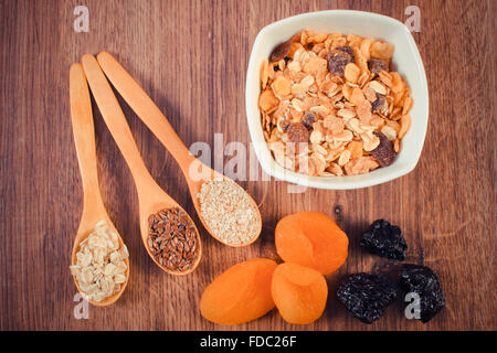 Vintage photo, Linseed, rye flakes and oat bran on spoon, dried fruits and muesli, concept of healthy nutrition Stock Photo