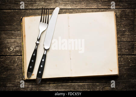 vintage book and cutlery on old wooden background Stock Photo