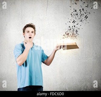 Young man with opened book and characters flying out Stock Photo