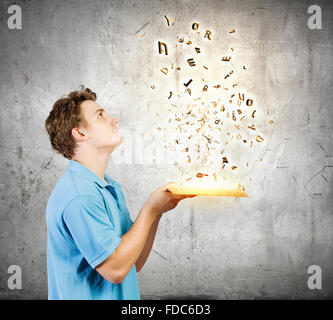 Young man with opened book and characters flying out Stock Photo