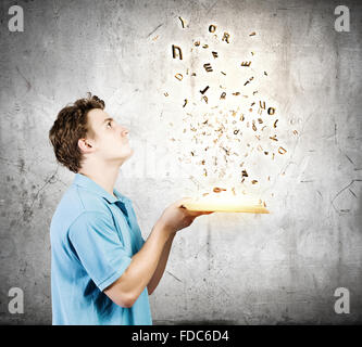 Young man with opened book and characters flying out Stock Photo