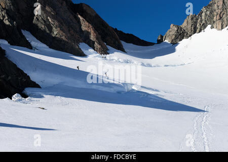 Group of people walking among snows of New Zealand mountains Stock Photo