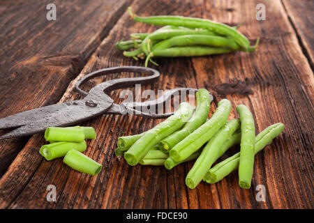 Raw fresh green beans with water drops on brown wooden textured table. Fresh vegetable eating. Stock Photo