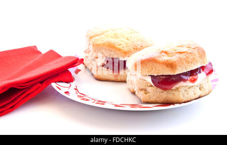 Home-baked scones with strawberry jam and clotted cream, often served with a cup of tea. Known as a cream tea. Stock Photo