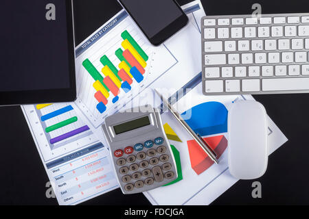 Modern workplace with digital tablet, pen, keyboard, mouse, smartphone and paper showing charts and diagram numbers on table. Stock Photo