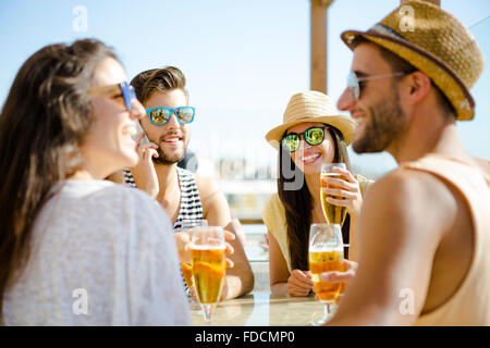 Friends having fun and drinking a cold beer at the beach bar Stock Photo