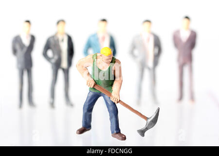 Miniature figurines of One worker and many White collar businessmen, concepts Stock Photo