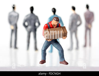 Miniature figurines of One worker and many White collar businessmen, concepts Stock Photo