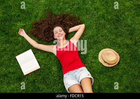 Beautiful and happy young woman lying on the grass Stock Photo
