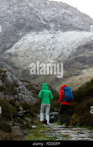 Snowdonia National Park, Gwynedd, Wales, UK. 30th January, 2016. Hikers climb the slopes near Llyn Ogwen. After an unseasonal mild spell, temperatures dropped to around zero this morning in Snowdonia National Park. A dusting of snow covers the peaks and there is a strong Westerly wind giving a much lower 'feels like' temperature. Credit:  Graham M. Lawrence/Alamy Live News. Stock Photo