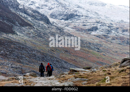 Snowdonia National Park, Gwynedd, Wales, UK. 30th January, 2016. Rock climbers descend near Llyn Ogwen at the end of the day. After an unseasonal mild spell, temperatures dropped to around zero this morning in Snowdonia National Park. A dusting of snow covers the peaks and there is a strong Westerly wind giving a much lower 'feels like' temperature. Credit:  Graham M. Lawrence/Alamy Live News. Stock Photo