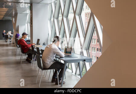 People working at desks and using computers in the Seattle Central Library, designed by Rem Koolhaas and Joshua Prince-Ramus Stock Photo