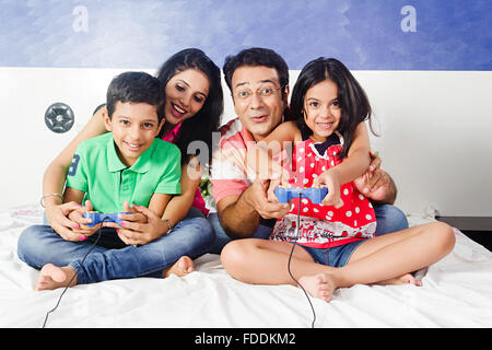 4 People Parents and Kid Bedroom Sitting Playing Video Game Stock Photo