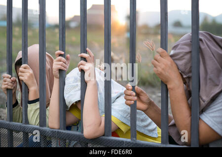 Concept immigrant crisis , Refugee peoples hand holding metal bar on refugee camp site Stock Photo