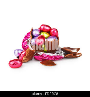 Broken chocolate easter egg wrapped in pink foil with colorful candies isolated on white background Stock Photo
