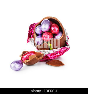 Broken chocolate easter egg wrapped in pink foil with colorful candies isolated on white background Stock Photo