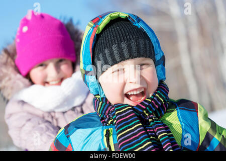 Boy and girl enjoying sledge ride in beautiful snowy winter park Stock Photo