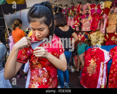 Bangkok, Bangkok, Thailand. 31st Jan, 2016. A woman tries on a traditional dress while she shops for new clothes at a stand on Yaowarat Road, in Bangkok's Chinatown district, before the celebration of the Lunar New Year. Chinese New Year, also called Lunar New Year or Tet (in Vietnamese communities) starts Monday February 8. The coming year will be the ''Year of the Monkey.'' Thailand has the largest overseas Chinese population in the world; about 14 percent of Thais are of Chinese ancestry and some Chinese holidays, especially Chinese New Year, are widely celebrated in Thailand. (Credit Imag Stock Photo